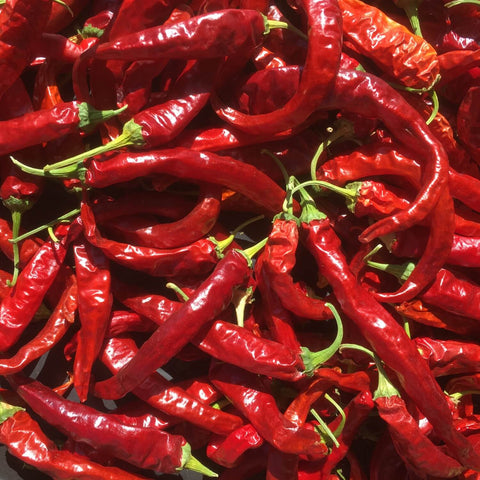 Close-up of red Korean hot peppers with green stems.