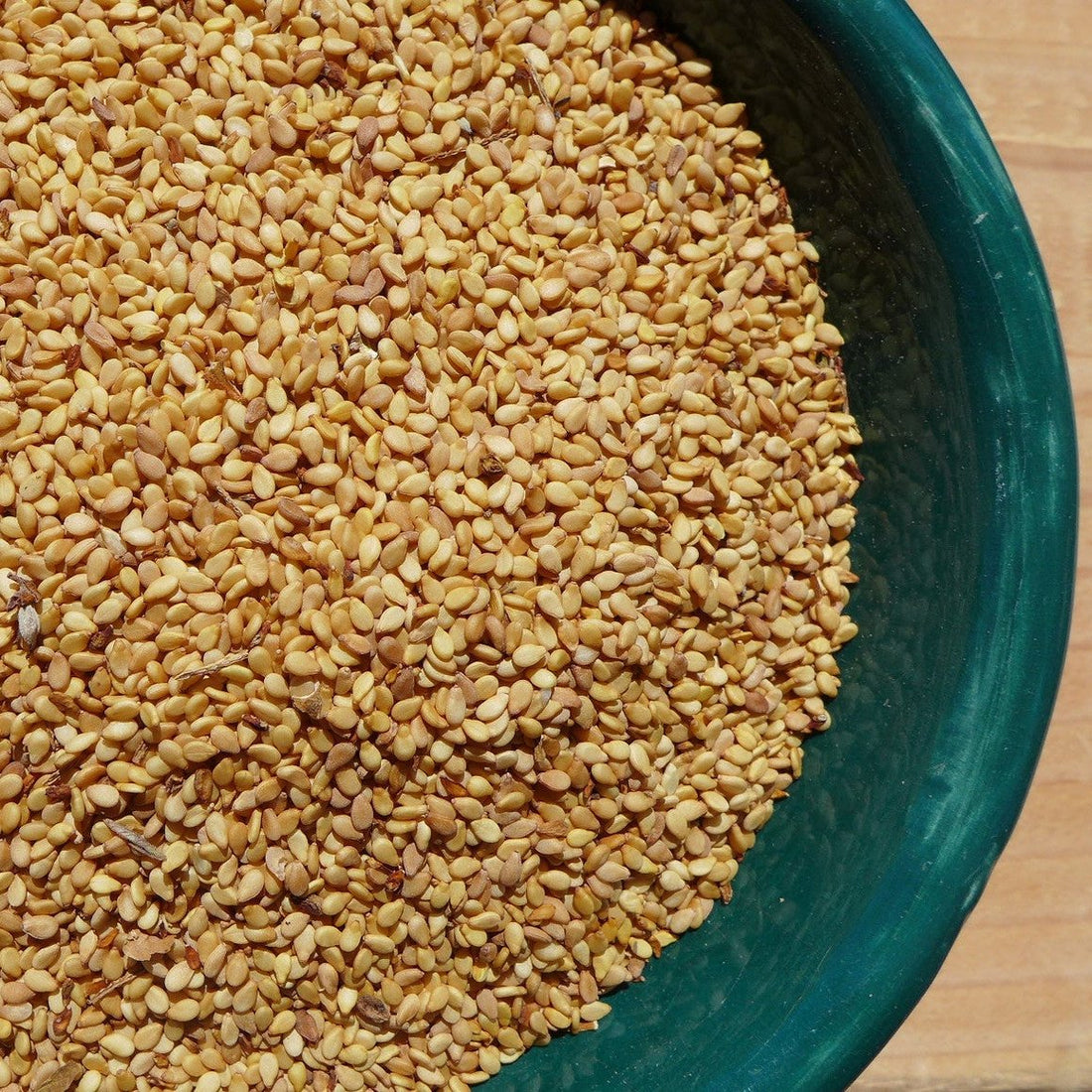 A bowl filled with tan sesame seeds.